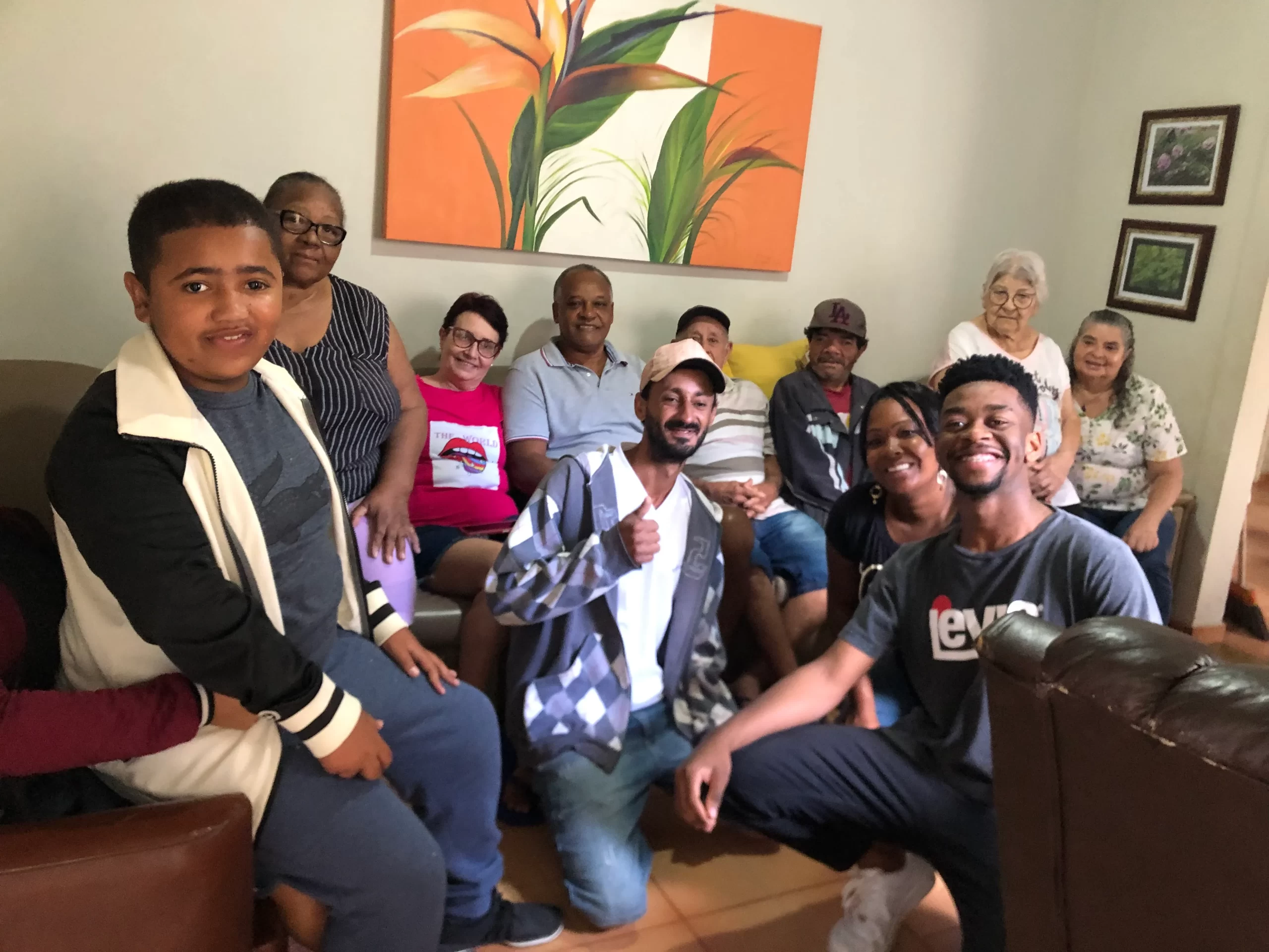 Assistidos, familiares e voluntários reunidos na sala de convivência da casa de apoio